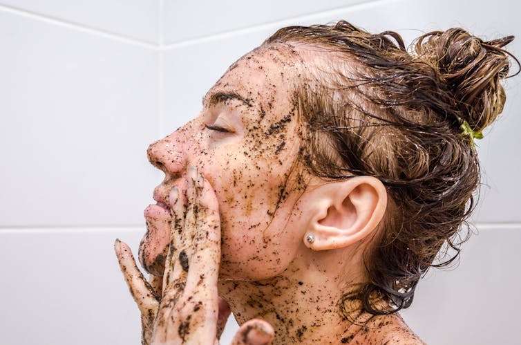 A woman uses a face scrub.