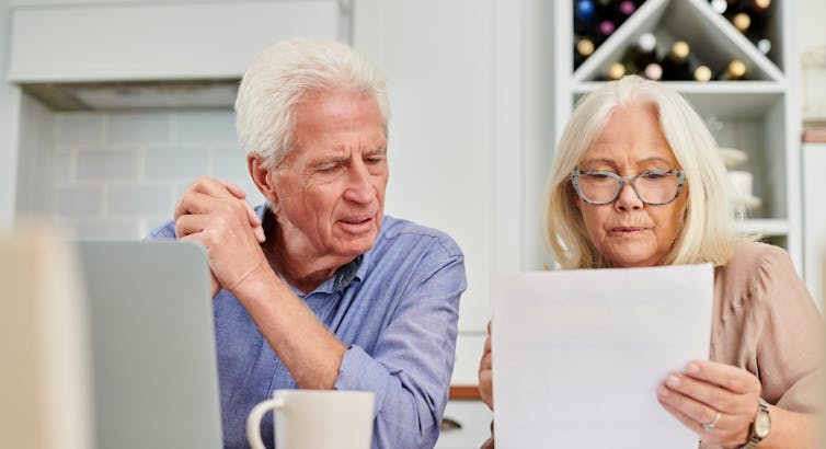 A senior couple looking unhappy while going through paperwork at home.