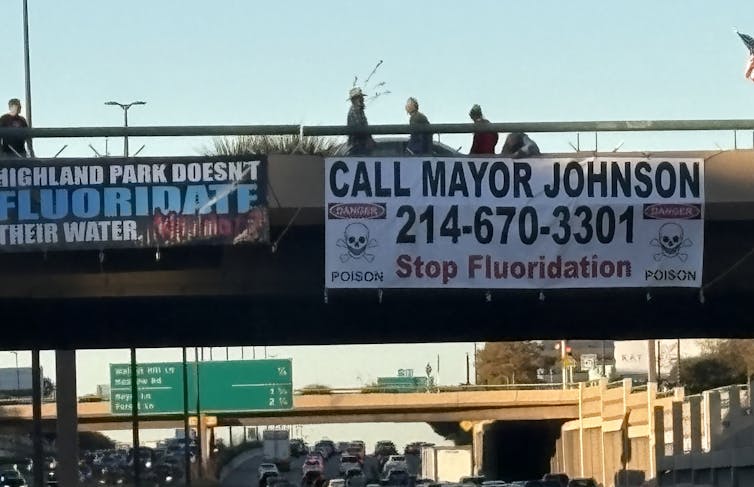 'Stop Fluoridation' banners hanging from freeway overpass.