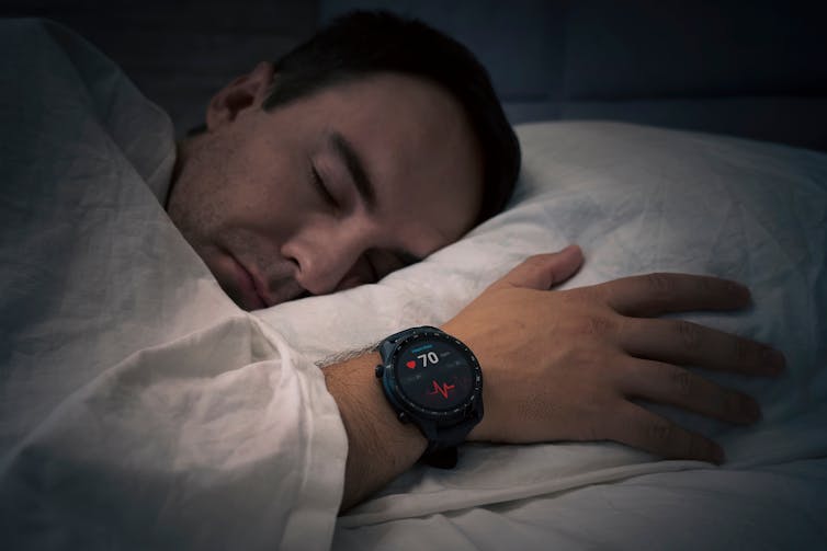 A man wearing an activity monitor on his wrist sleeps.