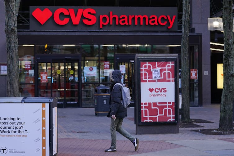 Person walking past CVS Pharmacy storefront