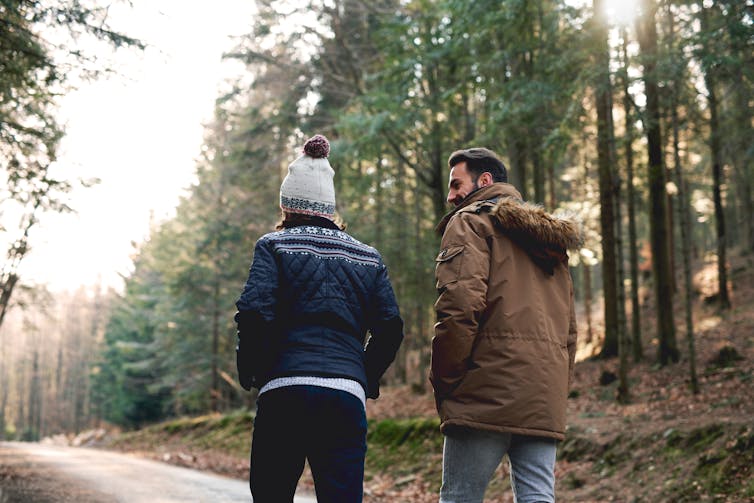 A man and woman go for a walk in the woods.