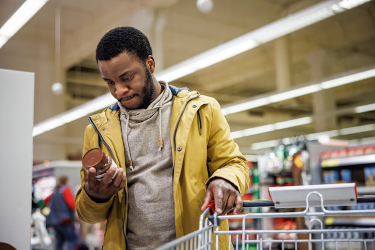 Person looking at nutrition label of nut butter product in grocery store