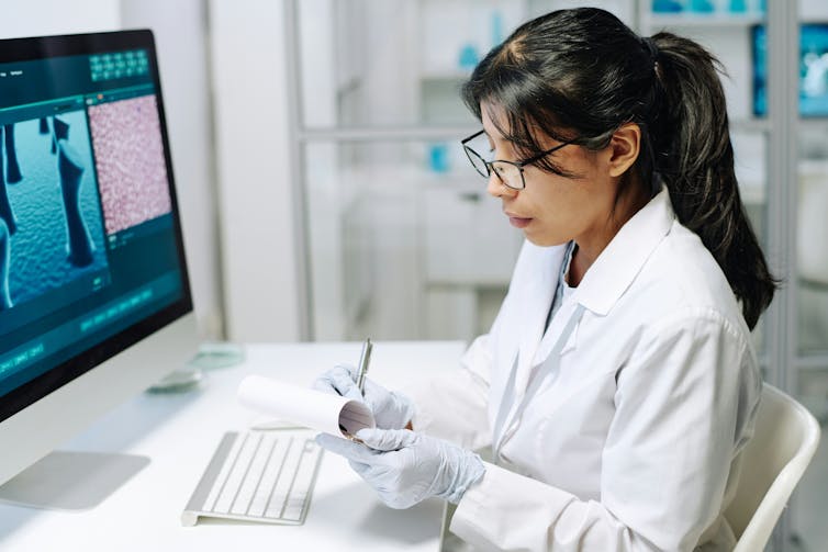 A researcher with a ponytail working at her desk.