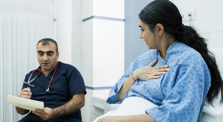 A doctor seated by the bed of a patient.