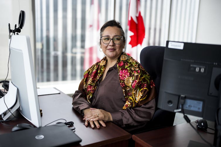 A woman sitting at her desk with hands crossed.