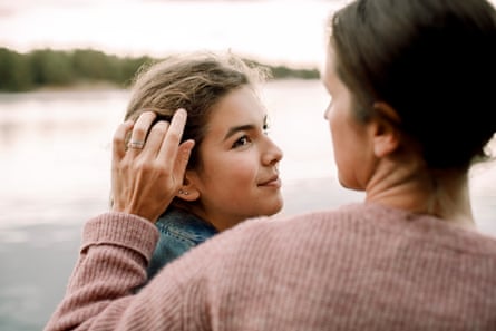 Smiling daughter looking at caring mother by lake.