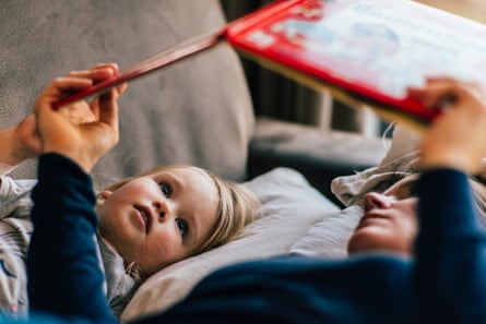 Mother and daughter reading book on a sofa.