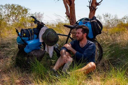 Graf rests under a tree with his bike in the Australian outback