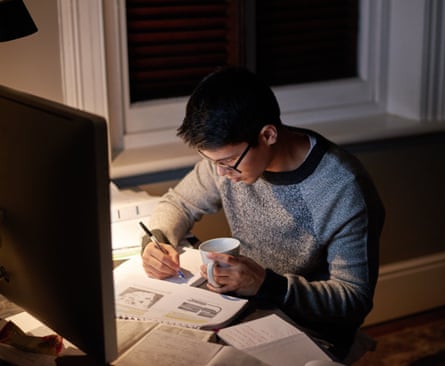 A young man sat writing at a desk