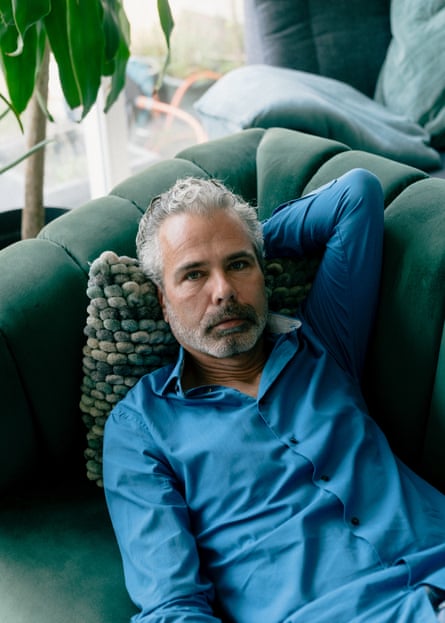 Dennis Biesma lies on a cushion on a green sofa, looking at the camera