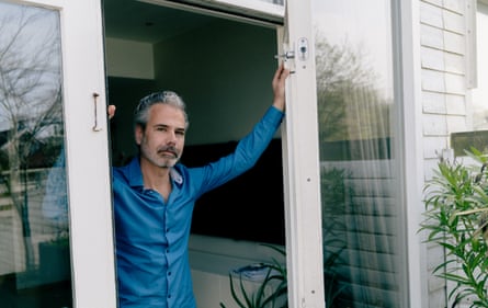 Dennis Biesma stands in the doorway of his home, wearing a blue shirt
