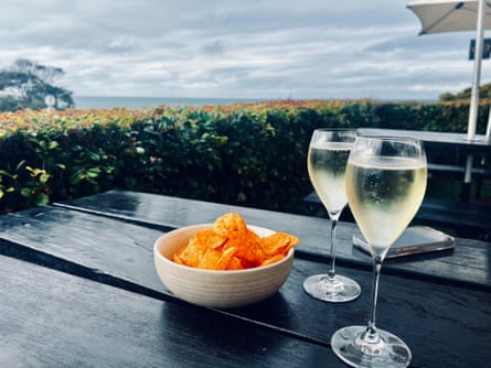 Chips in a bowl and two glasses of prosecco on a wooden table overlook the sea