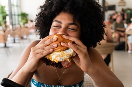 Woman enjoying a huge burger in a restaurant