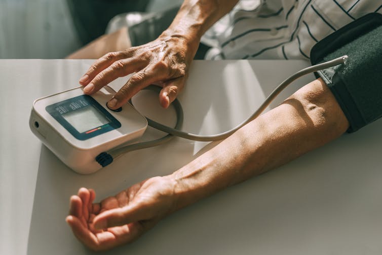 Close-up of arms of person measuring blood pressure with portable monitor