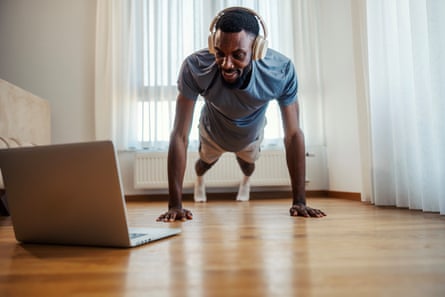 A man doing press ups at home looking at a laptop
