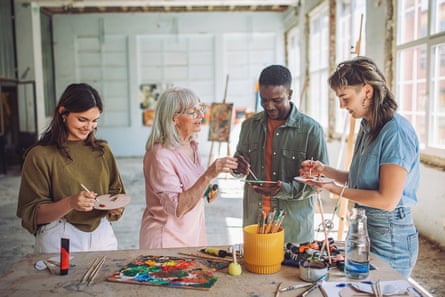 Art school teacher instructs enthusiastic students in a bright studio, sharing tips on canvas painting techniques and color mixing