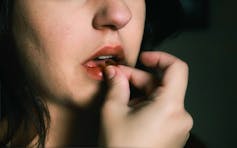 A teenage girl puts a pill in her mouth