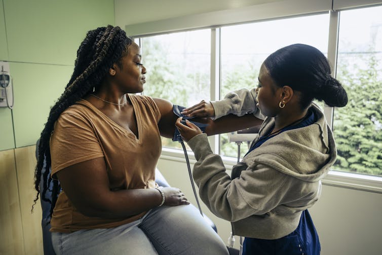 A Black female patient getting a blood pressure cuff put on her arm.