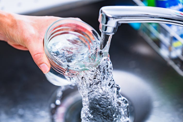 Hand filling glass with water from a faucet