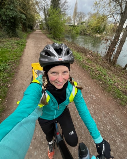 A woman takes a selfie while riding a bike alongside a river
