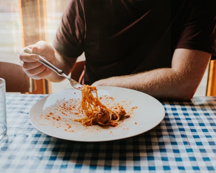 A person eating from a plate of pasta