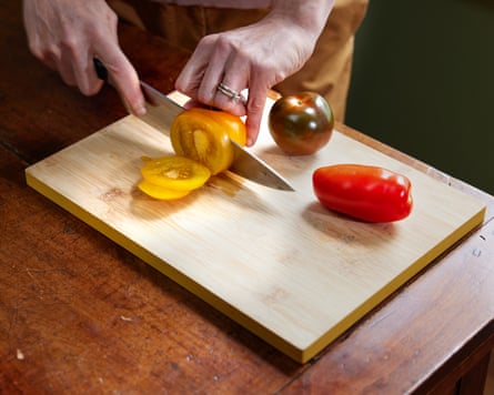Chopping yellow and red tomatoes on a wooden board.