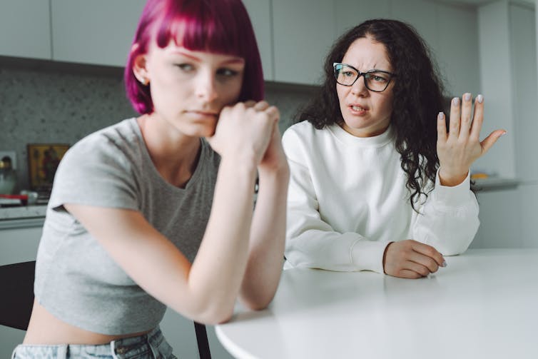 Single working mother and her teenage daughter talk with much emotion in the kitchen.