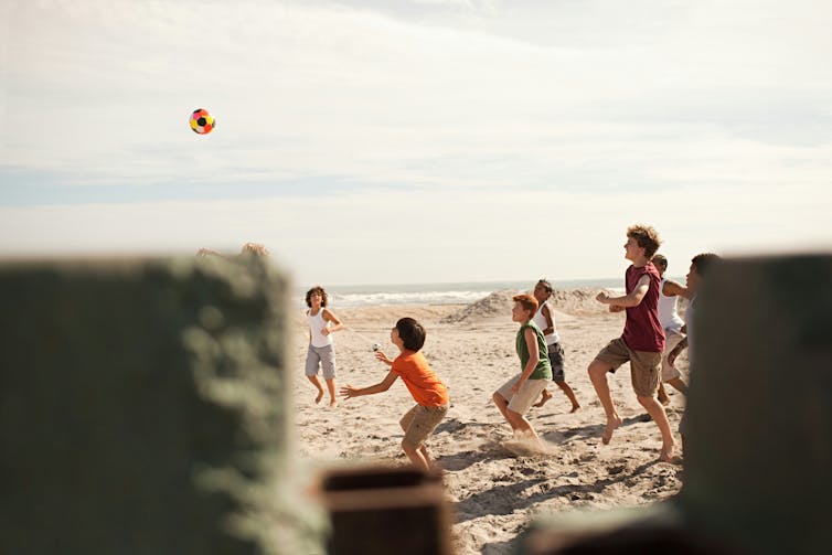 Children and an adult playing with a ball on a beach