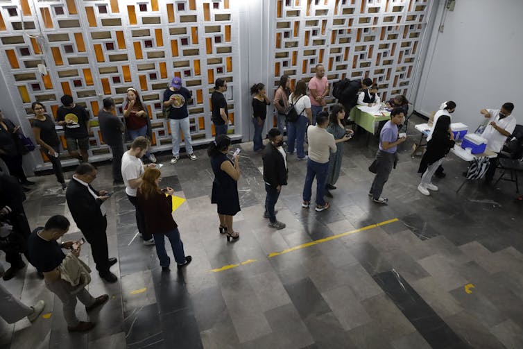 people stand in line for measles shots in a Mexican metro station