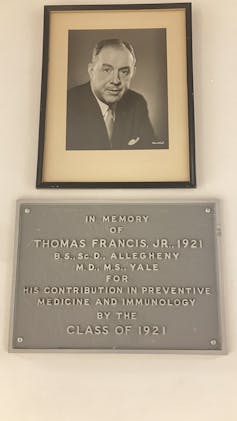 A photo and plaque hanging on a wall.