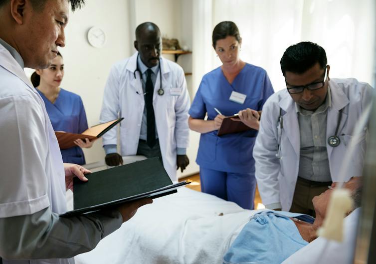 A group of health-care professionals surrounding a patient in a hospital bed