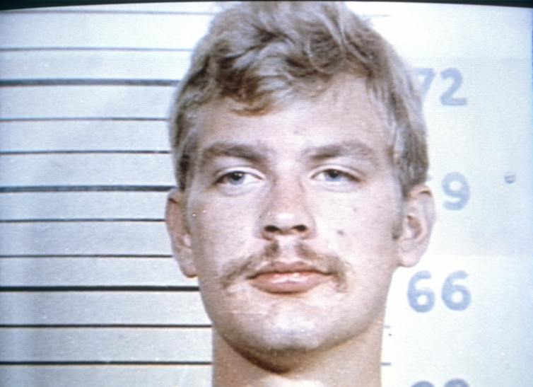 1980s-era mug shot of man with blonde hair and mustache