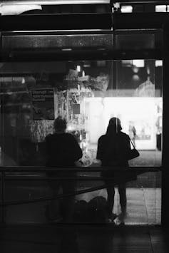 People silhouetted at a bus shelter in the dark.